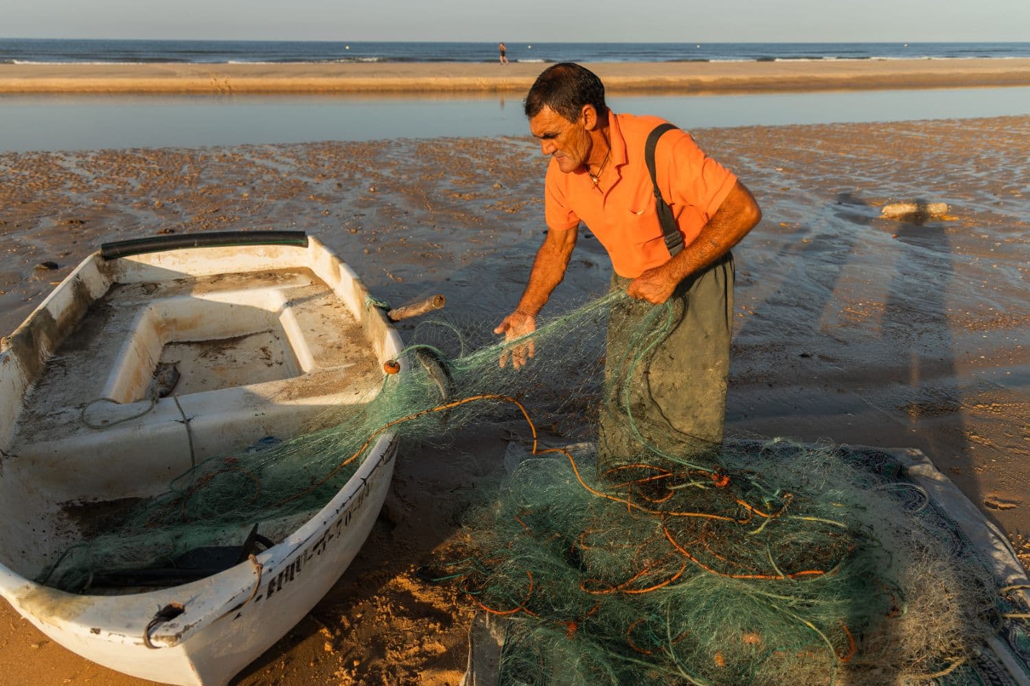 Fisherman preparing traditional fishing nets beside a small boat at Chengene Skele near Burgas