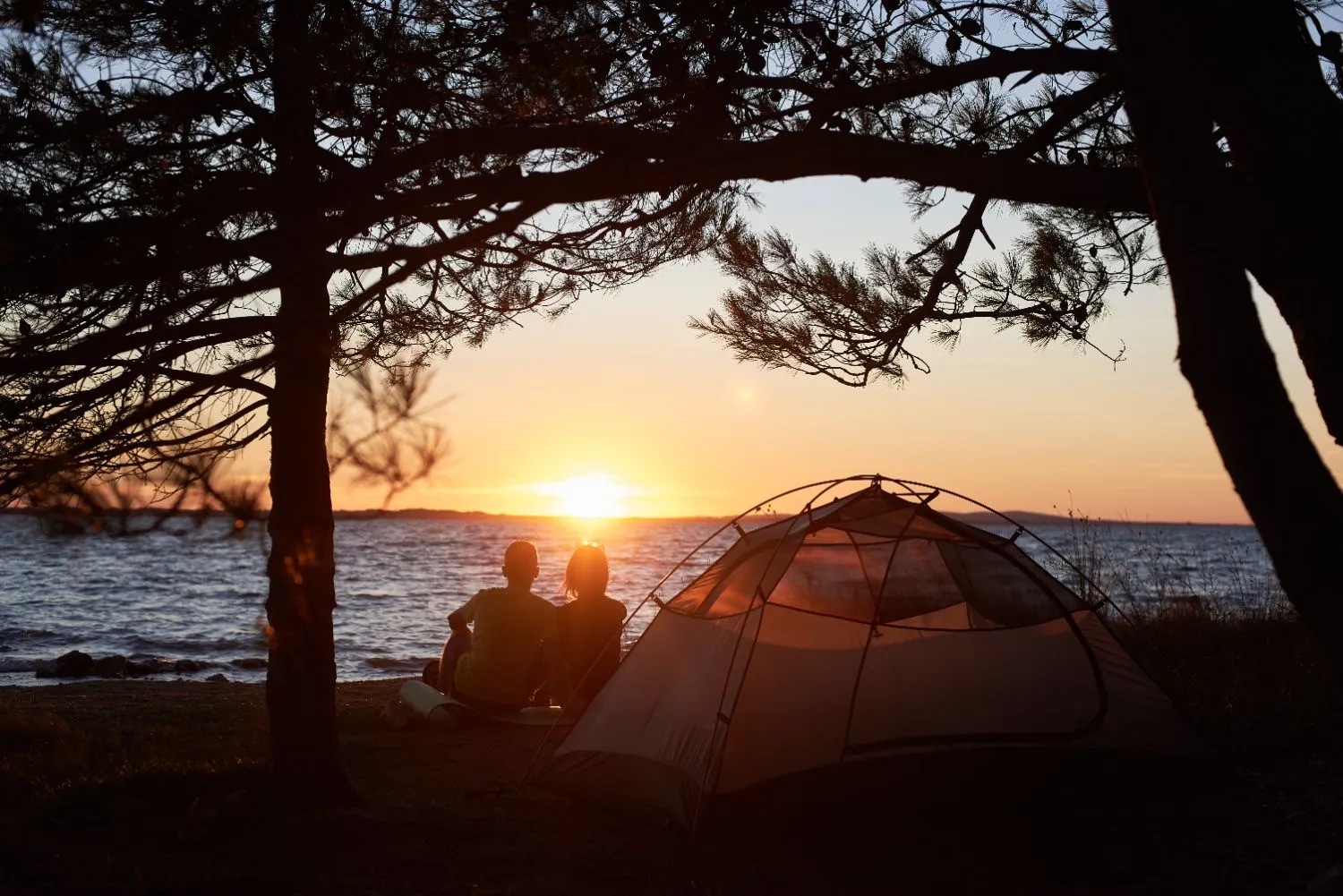 Camping for beginners with a seaside tent and a couple enjoying the sunset