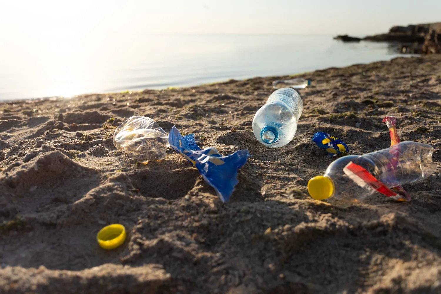 Déchets plastiques sur une plage de sable rappelant l'importance du camping responsable
