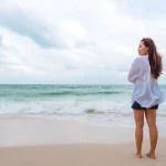 Frau genießt einen ruhigen Strandspaziergang unter bewölktem Himmel an der Schwarzmeerküste