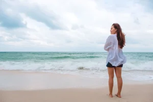 Frau genießt einen ruhigen Strandspaziergang unter bewölktem Himmel an der Schwarzmeerküste